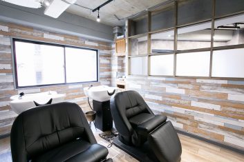 現代的なデザインの美容室内装、快適な黒のシャンプー椅子と洗髪台が備えられた清潔感のあるサロン空間