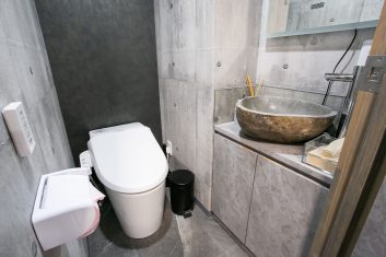 モダンなデザインのトイレと石製の洗面台が特徴的な洗面所の内装