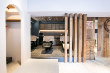 モダンで洗練された美容室の内装、木材とタイルを使用したデザイン、シャンプー台とヘアカット用チェアが備え付けられたリラックスできる空間