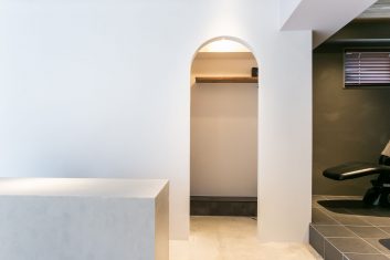 モダンな美容室の内装、アーチ型の入口とスタイリッシュな受付カウンターが特徴的なサロン空間
