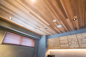 モダンで洗練された美容室のインテリアの一部で、木目調の天井、暖色のブラインドが特徴的な快適でリラックスできる空間
