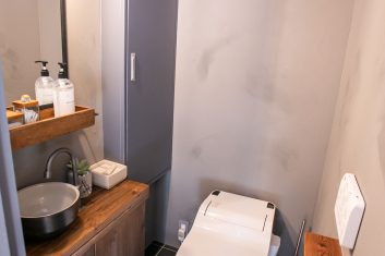 モダンな美容室のトイレットルーム内装、木目の洗面台とミラー、タイルの床、洗練されたデザインのトイレ設備