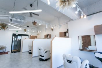 モダンなデザインの美容室内装、白と木目調のインテリア、シャンプー台と椅子が配置された快適な空間