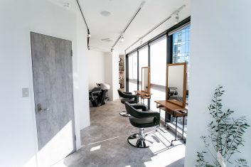モダンで洗練されたデザインの美容室内部、自然光が差し込む快適な空間にスタイリッシュな理髪席とシャンプー台