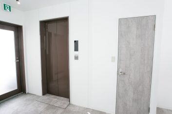 モダンな美容室の待合室のエレベーターと白い壁に囲まれた灰色のドア