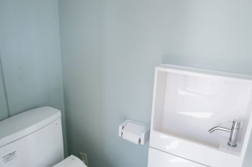 清潔でモダンなデザインの美容室のトイレ設備、白い陶器の洗面台とトイレが備え付けられた落ち着いた空間