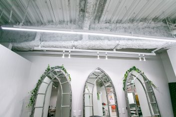 モダンな美容室の内装で、ゴシック様式のアーチ型鏡と露出した天井が特徴的な空間